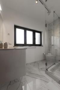 een witte badkamer met een douche en een raam bij Pérola do Mar in Foz do Arelho +13 foto's