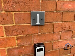 een bakstenen muur met het nummer één erop bij Coach House at The George Pub, Ashley, Market Harborough in Ashley