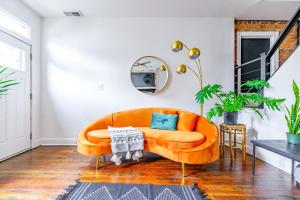 a living room with a orange couch and a mirror at Jungle House Luxury Homes - Columbus Downtown Short North - Steps to Convention Center & Nationwide Arena - Sleeps up to 10 - Free Parking - Over 5,800 Five Stars in Columbus