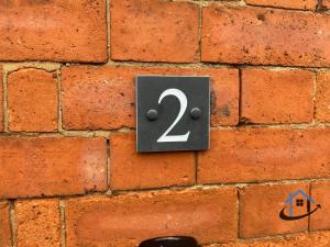 een bord op een stenen muur met het nummer twee bij Coach House at The George Pub, Ashley, Market Harborough in Ashley