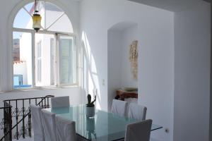 ein Esszimmer mit einem Glastisch und einem Fenster in der Unterkunft The White House 1 in Ándros