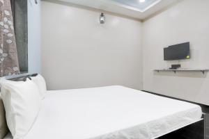 a white room with a bed and a flat screen tv at Hotel O Raj Guest House in Akola +22 photos