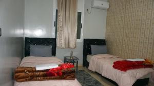 um quarto com duas camas com cobertores vermelhos em Hotel adrar em Tafraoute