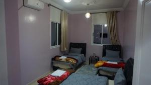 um pequeno quarto com 2 camas e um sofá em Hotel adrar em Tafraoute