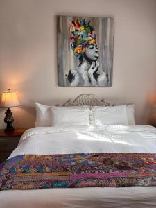 Caye Caulker Boutique Guesthouse 7 في كاي كولكر: غرفة نوم بها سرير ولوحة على الحائط