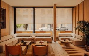 una sala de estar con sofás, mesas y una gran ventana. en Aethos London Shoreditch, en Londres 85 fotos más