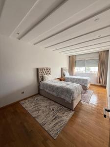 two beds in a large room with wooden floors at Apartment luxurious a Hay Riad in Rabat