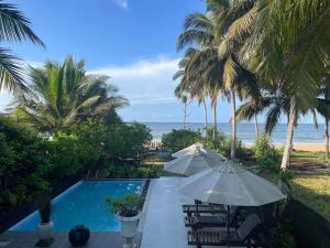 um resort com piscina, palmeiras e oceano em Endlessblue Resort Kalametiya em Kalametiya