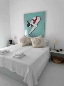 ein Schlafzimmer mit einem weißen Bett mit einem Bild an der Wand in der Unterkunft The White House 1 in Ándros + 38 Fotos