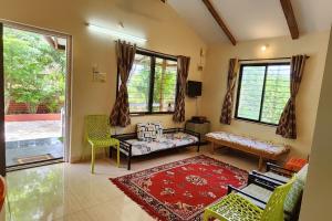 uma sala de estar com um sofá, cadeiras e janelas em Gulmohar Villa tamhini ghat, Kolad Rafting  mais 33 fotografias