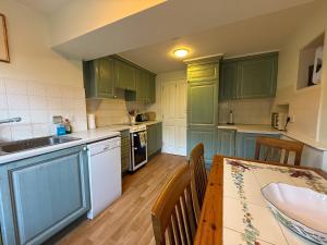 a kitchen with green cabinets and a wooden table at Thin End in Seaview