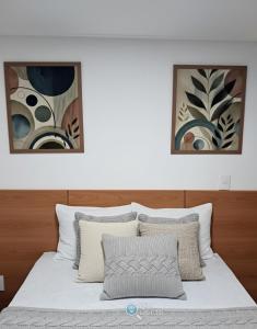 uma cama branca com duas fotografias na parede em Hit Cabo Branco by 123Quarto em Tambaú