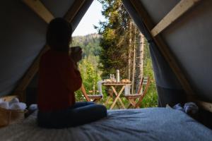 a woman sitting on a bed in a tent looking at a table at Campeggio Treinke Sauris in Sauris