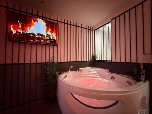bagno con vasca e TV a parete di The Forbidden Suite - prison a Souppes-sur-Loing