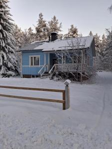 Traditional Finnish Lapland house at wild forest backyard! في كيمي: بيت أزرق في الثلج بجوار سياج