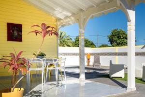 a patio with a table and chairs on a yellow house at Villa Guenaslo 1 in Saint-François +27 photos
