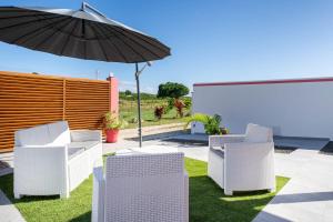 a patio with white chairs and an umbrella at Villa Guenaslo 2 in Saint-François