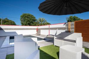 a patio with white chairs and an umbrella at Villa Guenaslo 2 in Saint-François