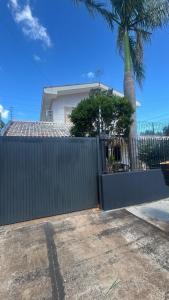 a fence in front of a house with a palm tree at Med House in Guaíra