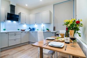 a kitchen with white cabinets and a wooden table at Enigma Lodge in Stratford-upon-Avon