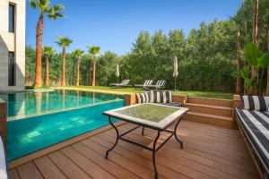 a swimming pool with a table and chairs on a deck at Palais Zahira in Marrakesh +50 photos