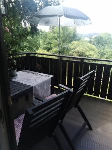 a table and chairs on a deck with an umbrella at Ferienhaus Bärenloch in Hilders