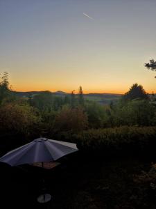 an umbrella sitting in the shade with the sunset in the background at Ferienhaus Bärenloch in Hilders +7 photos