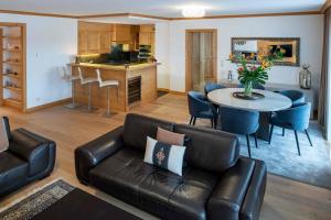 a living room with a leather couch and a table at Chalet RoyAlp Hôtel & Spa in Villars-sur-Ollon