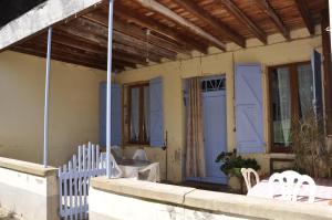 Ferme Les Pigeonnières في Canals: منزل بأبواب زرقاء وكراسي بيضاء على الشرفة