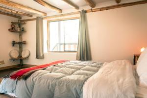 Un dormitorio con una cama grande con ventana. en Ninakancha - centro de retiro y sanación, en Coya