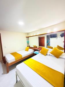 a room with three beds with yellow pillows at Hotel San Vicente in Medellín