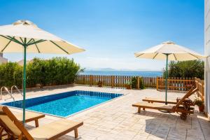 a swimming pool with two chairs and two umbrellas at Villa Alya View in Barbati