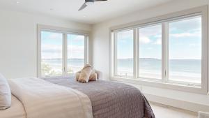 een slaapkamer met ramen en een bed met een knuffeldier erop. bij Tidal House in Surfside