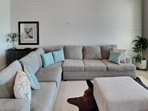 a living room with a gray couch and blue pillows at Serenity At Port A in Port Aransas