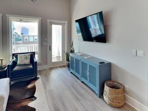 a living room with a blue cabinet and a flat screen tv at Serenity At Port A in Port Aransas
