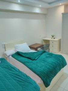 a bedroom with a bed with a green blanket at رويال للغرف الفندقية in Mît Khamîs
