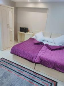 a bed with a purple comforter in a room at رويال للغرف الفندقية in Mît Khamîs