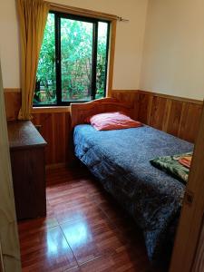 een kleine slaapkamer met een bed en een raam bij Cabañas Mis Nietos in Licán Ray