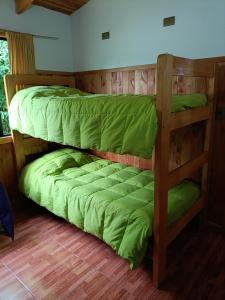 2 stapelbedden in een kamer met groene lakens bij Cabañas Mis Nietos in Licán Ray