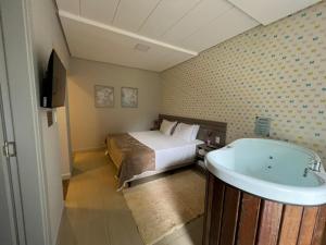 um quarto de hotel com uma cama e uma banheira em Recanto Catarina em Cascavel
