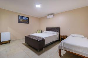 ein Schlafzimmer mit 2 Betten und einem Stuhl darin in der Unterkunft Pousada Dona Bili in Pirenópolis + 35 Fotos