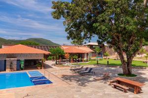 a resort with a pool and benches and a tree at Pousada Dona Bili in Pirenópolis