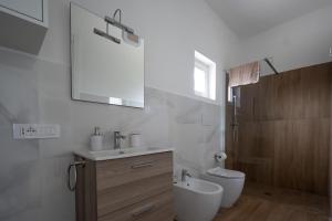 een badkamer met een wastafel, een toilet en een spiegel bij Casa di Viola - Ortensia in Latina