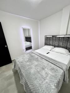 Un dormitorio blanco con una cama grande y un espejo. en GM Suites, en Cúcuta