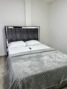 1 cama con cabecero negro y sábanas blancas en GM Suites, en Cúcuta 12 fotos más