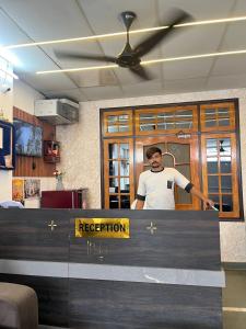 un uomo è in piedi dietro un bancone della reception di Staylo master Inn a Lucknow
