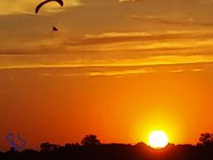 an orange sunset with a kite flying in the sky at Departamentos Rimasha in Federación +1 photo