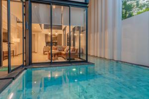 een zwembad in een huis met glazen wanden bij Maya Luxury Pool Villa Inara in Pattaya South