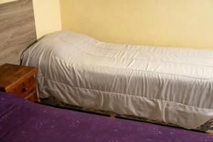 an unmade bed in a room with a table at Keóken - Frente al Hiper Tehuelche in Caleta Olivia