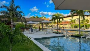 una piscina del complejo con sillas, mesas y palmeras en Pipa de oliveiras, en Pipa